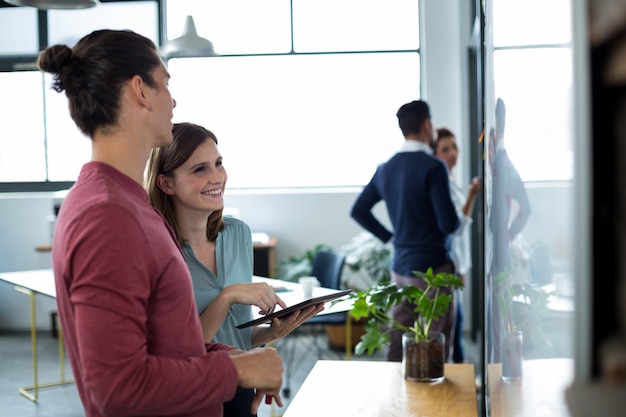 Directeuren die over digitale tablet in bureau bespreken