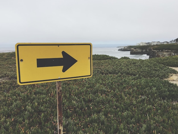 Photo directional sign at beach against sky