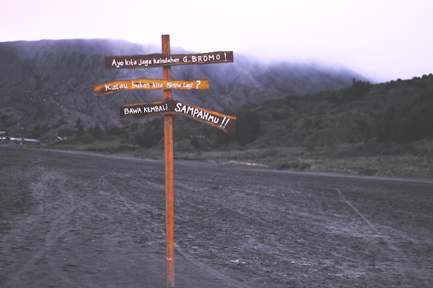 Photo directional sign on road with mountains in background