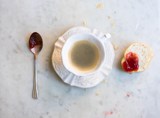 写真 バゲットとスプーンでストロベリージャムでコーヒーの直接上のショット