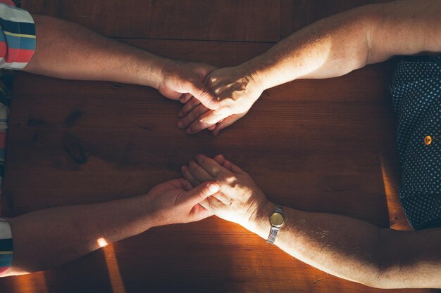 写真 テーブルの上で手をつないでいるカップルの直接上のショット