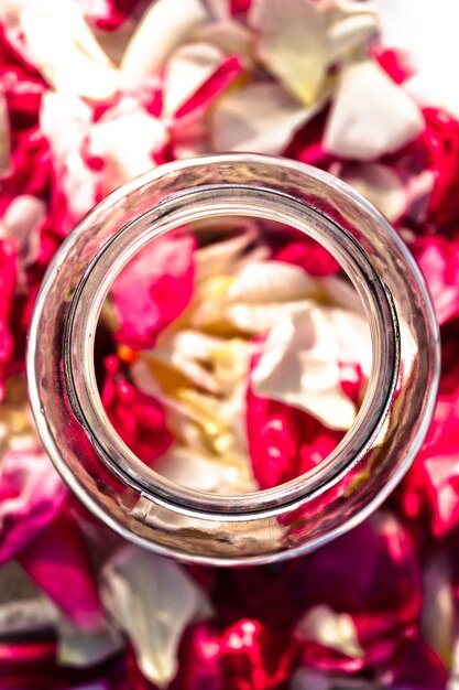 写真 テーブルの上のバラの花びらの中のガラスの瓶の直接上のショット
