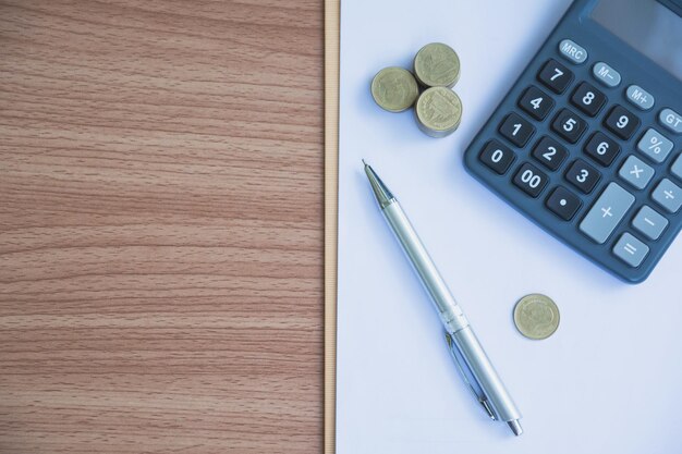 Фото Прямо над ручкой с монетами и калькулятором над бумагой на столе