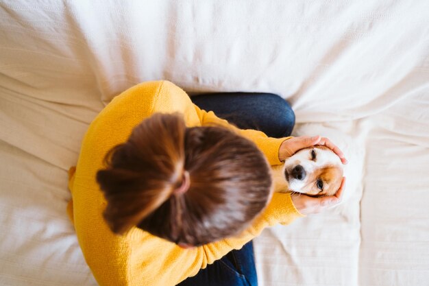 写真 ベッドの上に子犬と一緒に座っている女性の直接上のショット