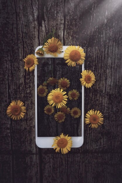 Фото Прямо над снимком желтых цветов через смартфон на столе