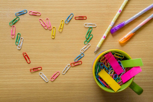 directly above paper clips forming heart shape by school supplies on table