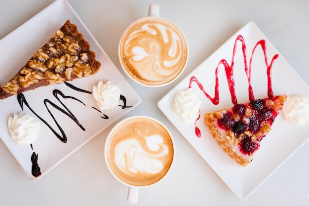 Photo directly above of pastry with cappuccinos served on table