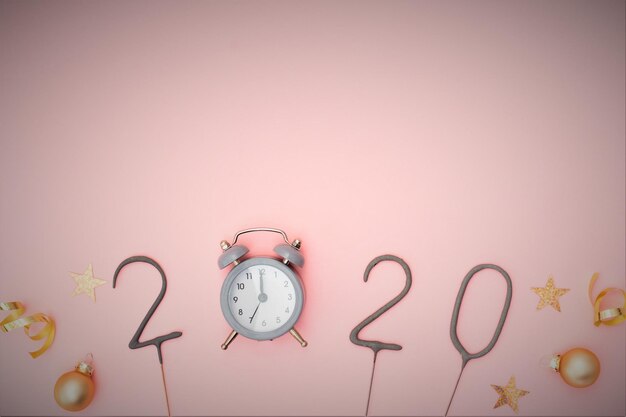 Photo directly above shot of alarm clock with christmas decoration over pink background