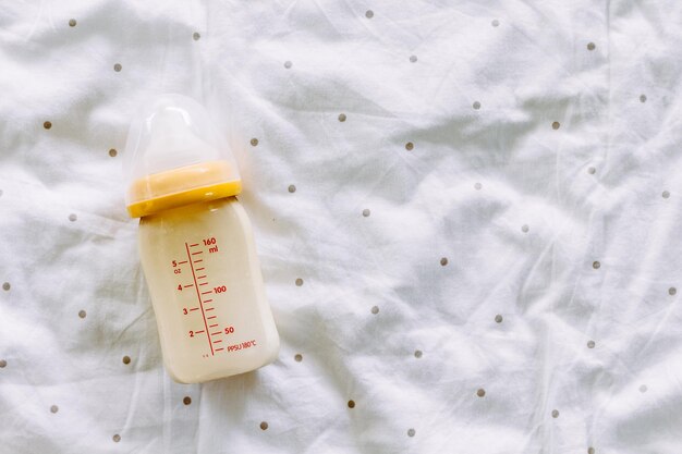 Photo directly above shot of baby bottle on bed