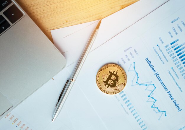 Photo directly above shot of bitcoin by pen on documents at desk