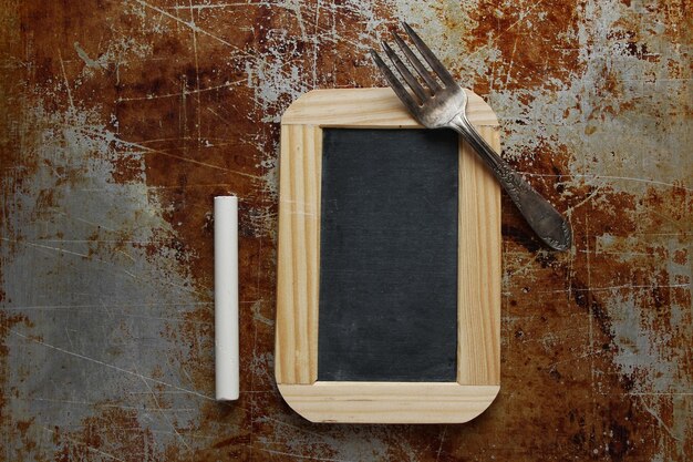 Photo directly above shot of blackboard and chalk with fork on rusty metal