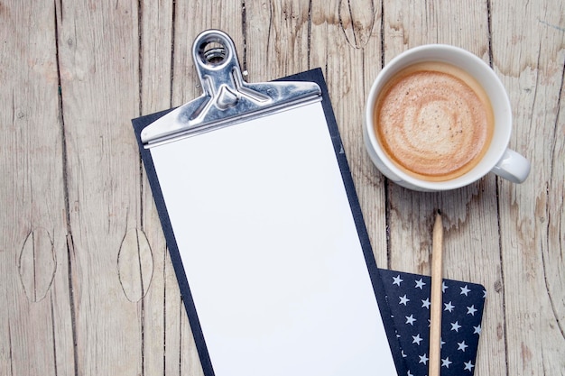 Photo directly above shot of blank paper in clipboard with coffee cup on wooden table