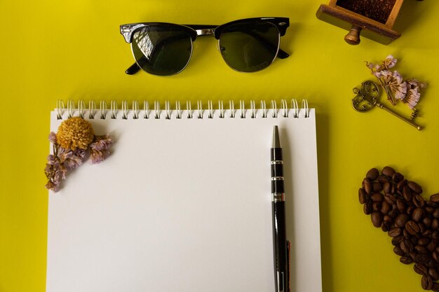 Directly above shot of book with pen and eyeglasses by roasted coffee beans on yellow table