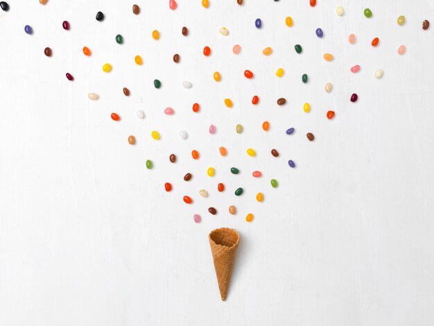 Photo directly above shot of candies and ice cream cone arranged on white background