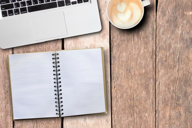 Directly above shot of cappuccino with laptop and notebook on table