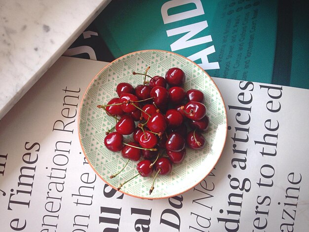 Photo directly above shot of cherries in plate on book