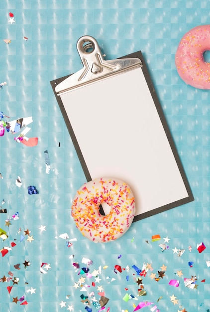 Photo directly above shot of clipboard with donuts and colorful confetti on table