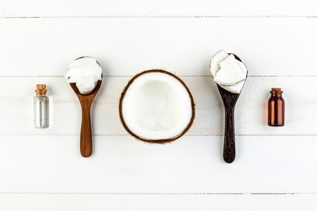 Directly above shot of coconut by wooden spoons and bottles on table