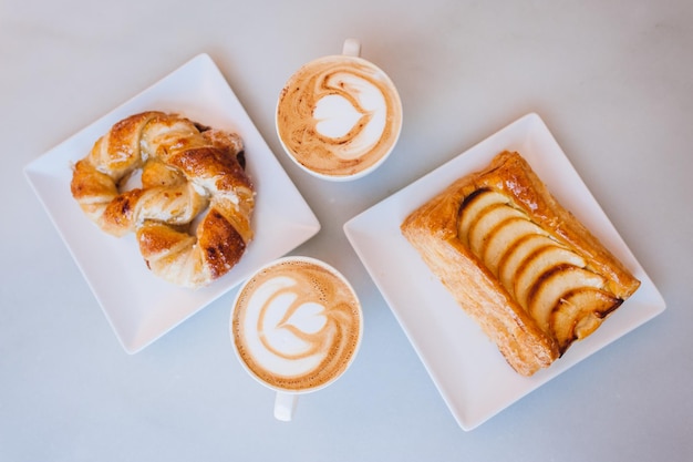 カフェのテーブル上のデザートの中のコーヒーカップの直接上のショット