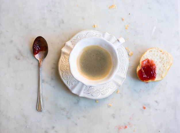 バゲットとスプーンでストロベリージャムでコーヒーの直接上のショット