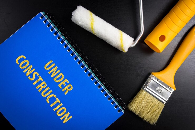 फोटो directly above shot of under construction text on book by paintbrush and paint roller