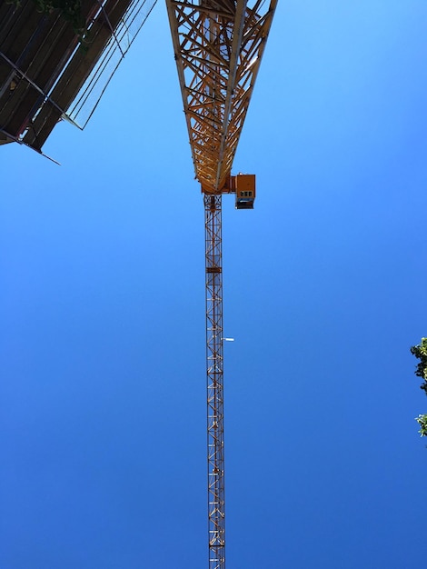 Directly below shot of crane against clear blue sky