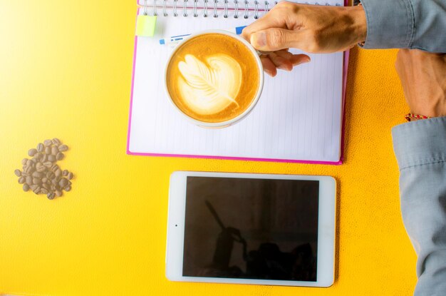 Directly above shot of cropped hands holding coffee cup at table