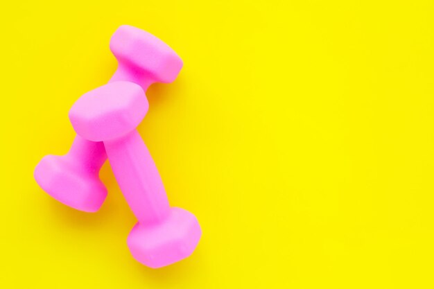 Directly above shot of dumbbells over yellow background