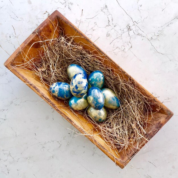 Directly above shot of easter eggs and hay in container on table