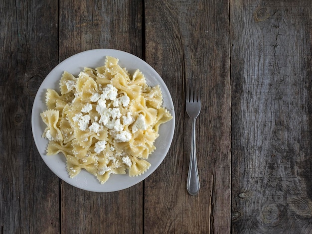 Directly above shot of farfalle pasta with cheese in plate on wooden table