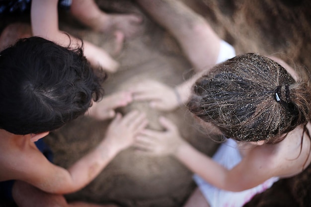 Photo directly above shot of friends playing with sand at beach