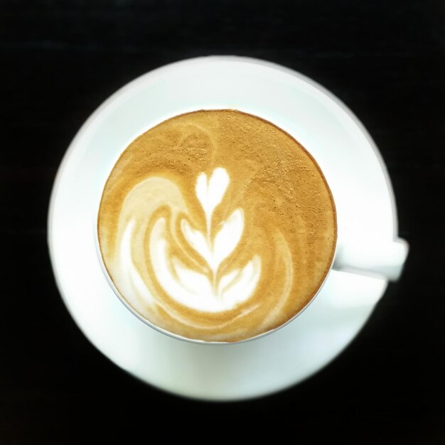 Directly above shot of froth art on coffee over black background