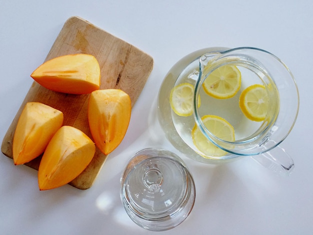 Directly above shot of fruit slices on cutting board with lemons in container on table