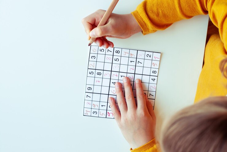 Photo directly above shot of girl doing sudoku puzzle