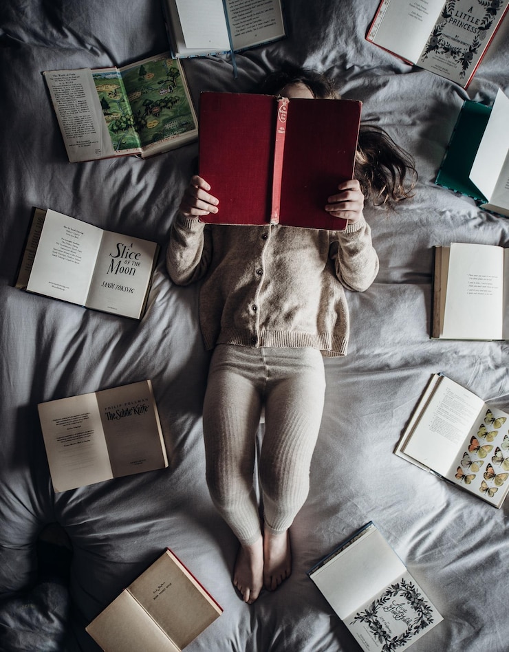 Photo ベッドで本を読んでいる女の子の直接上のショット