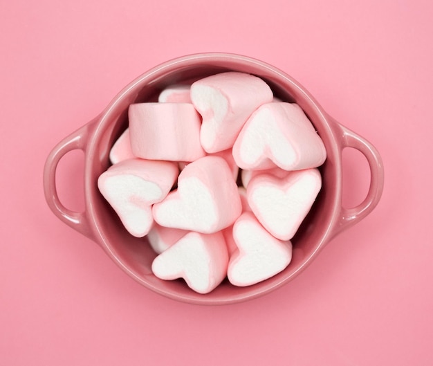 Photo directly above shot of heart shaped marshmallows in bowl on pink table