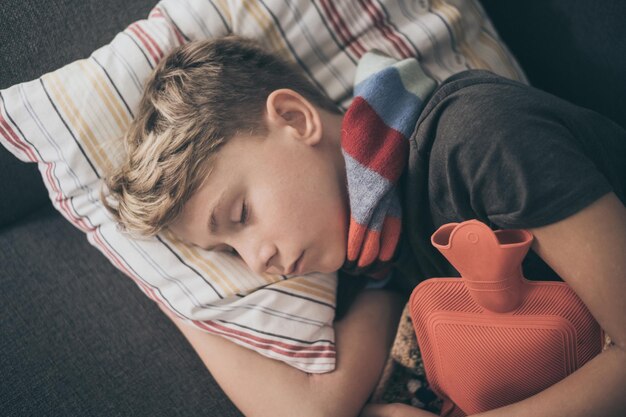 Photo directly above shot of ill boy sleeping on sofa at home