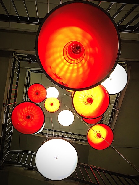 Photo directly below shot of illuminated lamps hanging from spiral staircase