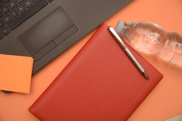 Photo directly above shot of laptop and diary on orange background