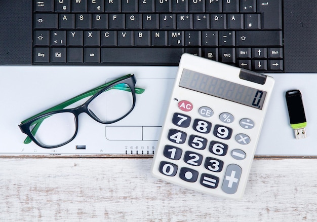 Directly above shot of laptop with eyeglasses and stationary on white table