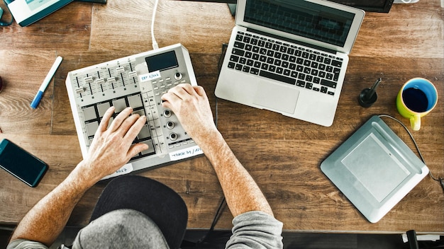 Photo directly above shot of man operating musical equipment at desk