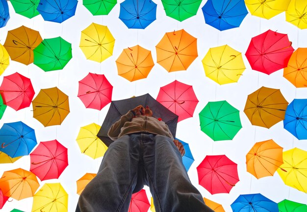 Photo directly below shot of man standing against colorful umbrellas