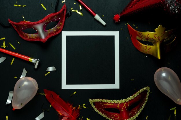 Directly above shot of mask and balloons with frame over black background