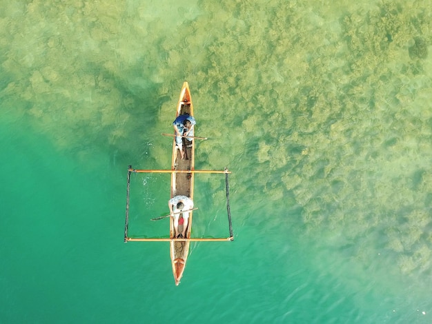 Foto direttamente sopra scatto di uomini su barca a coda lunga che navigano in mare