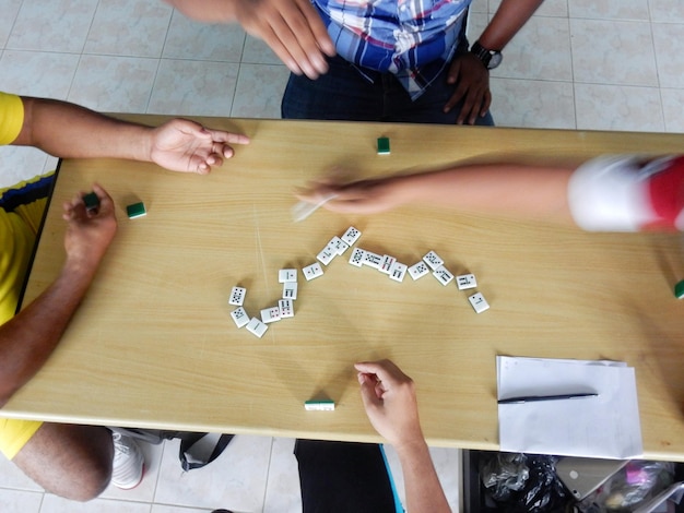 Photo directly above shot of men playing dominoes on wooden table