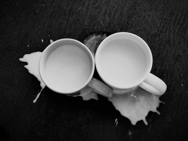 Directly above shot of milk in coffee cups on table