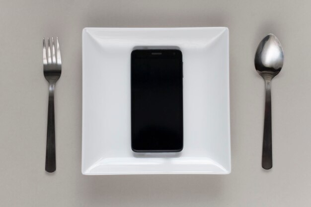 Photo directly above shot of mobile phone in plate on gray background