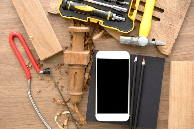 Foto scatto direttamente sopra del telefono cellulare con legno e utensili a mano sul tavolo