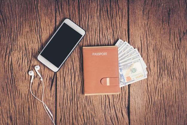 Foto direttamente sopra il colpo di denaro con passaporto e telefono cellulare su un tavolo di legno