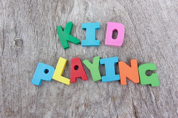 Photo directly above shot of multi colored alphabet blocks with kid playing wording on wooden background